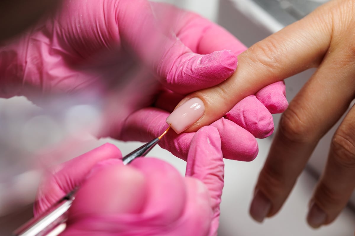 Close-up view of a beauty professional working on a client's hand during manicure procedure