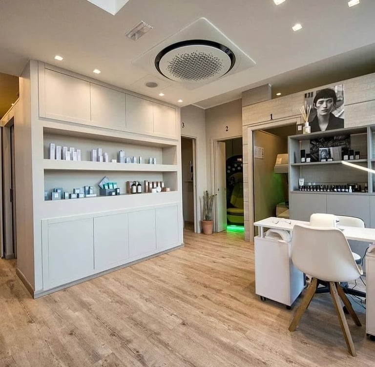 Modern beauty salon interior with white cabinetry, product shelves, wooden flooring, and a consultation seating area