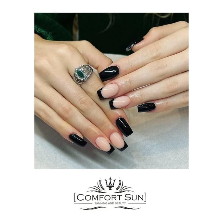 Manicured nails featuring black and nude ombre design with decorative silver ring, displayed on gray surface with Comfort Sun salon logo