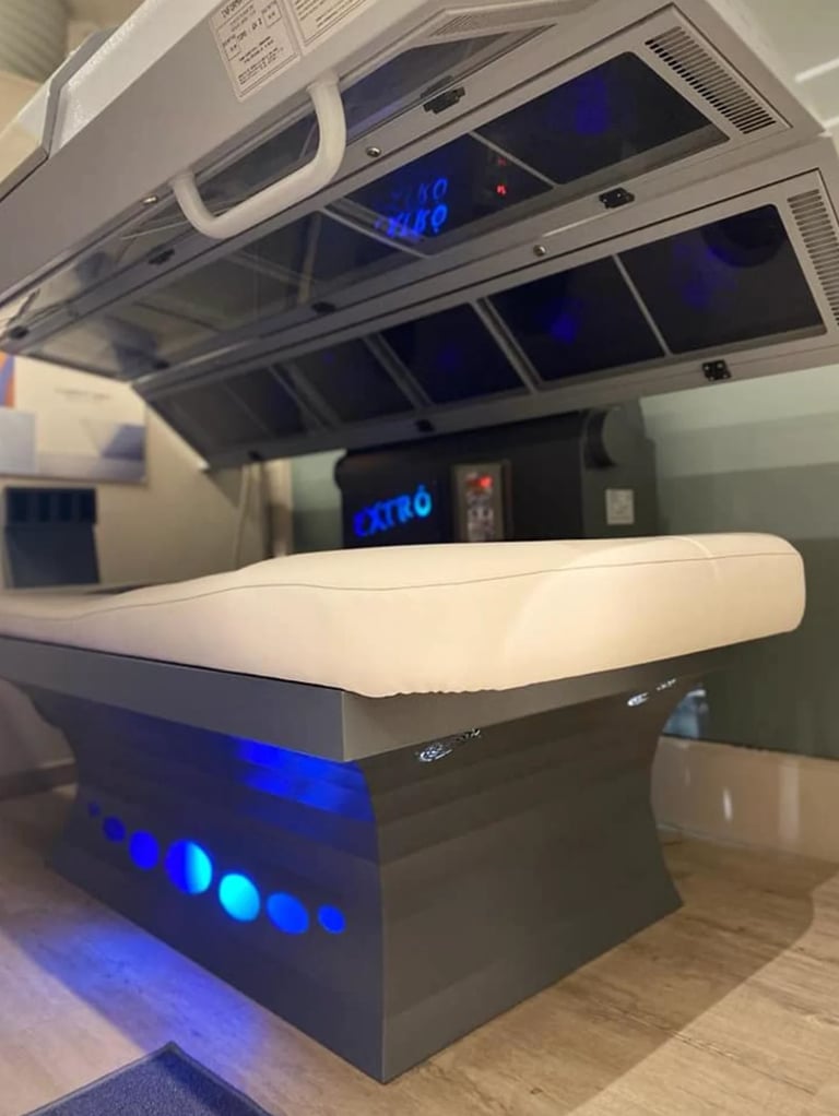Modern medical imaging scanner with blue illuminated display and white padded table in clinical setting